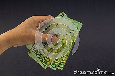 Hand holding saudi riyal bank notes on black background. Stock Photo