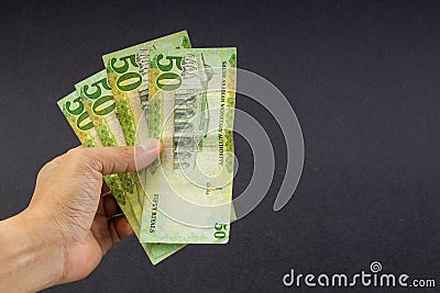 Hand holding saudi riyal bank notes on black background. Stock Photo