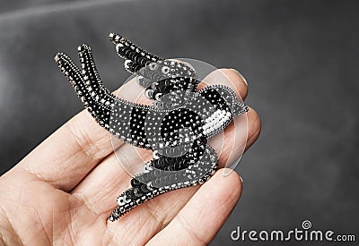 Hand holding seed bead embroidered brooch in a shape of black swallow bird Stock Photo