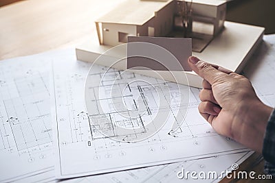 A hand holding and showing an empty business card with an architecture model and shop drawing paper on table Stock Photo