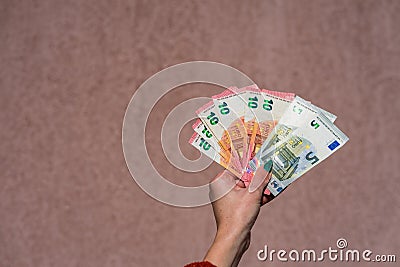 Hand holding showing euro money and giving or receiving money like tips, salary. 5 and 10 EURO banknotes EUR currency . Stock Photo