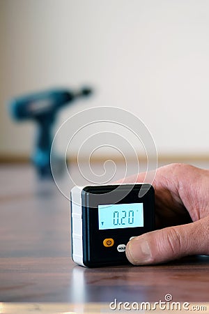 Hand holding a small digital spirit level on parquet floor. Stock Photo