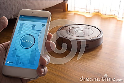 Hand holding smartphone with application control robot vacuum cleaner Stock Photo