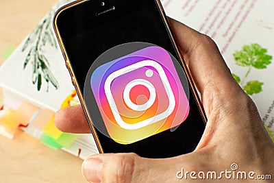 Hand holding a smartphone with an Instagram icon on screen. Editorial Stock Photo