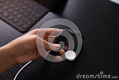 Hand holding smartwatch recharge in wireless charger Stock Photo