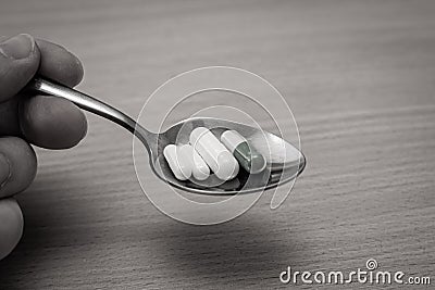 Hand holding a spoon of drugs. Eating antidepressants concept Stock Photo