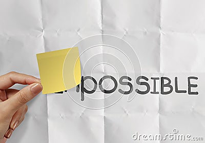 Hand holding sticky note over word impossible transformed Stock Photo
