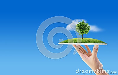 Hand holding tablet computer with grass and tree of nature background with environment concept. Stock Photo