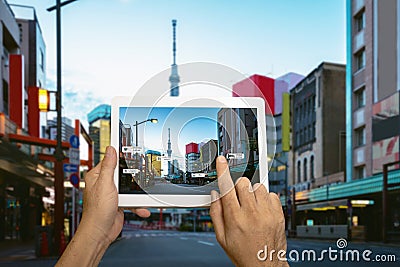 Hand holding tablet use AR application to check relevant information. Japan City in marketing street Stock Photo