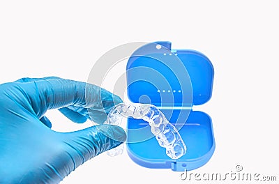 Hand holding transparent individual dental tray for teeth whitening in front of the dental container Stock Photo