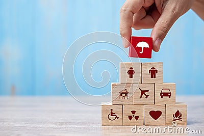 Hand holding umbrella wood block cover Insurance icon. healthcare medical, life, car, home, travel insurance concept Stock Photo