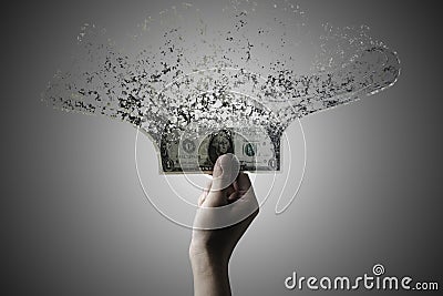 Hand holding US dollar banknote which it is disintegrate into dust particles for money hyper inflation and decreasing power of Stock Photo