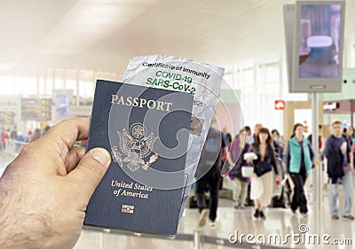 Hand holding a US passport with a wrinkled paper Coronavirus Covid 19 immunity certificate blurred airport in the background Stock Photo