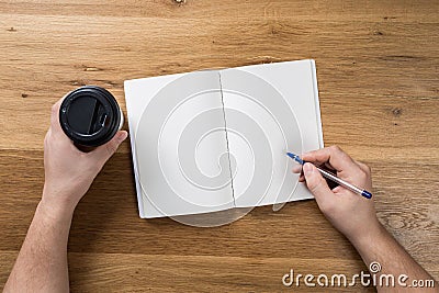 Hand holding white blank paper sheet mockup on wooden background Stock Photo