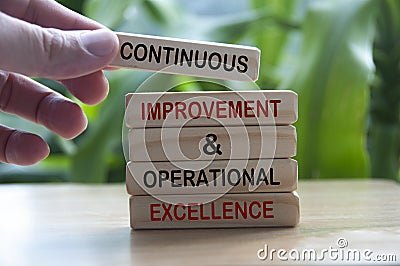 Hand holding wooden blocks with text - Continuous improvement and operational excellence. Stock Photo