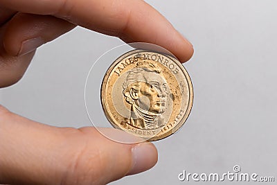 A hand holds a coin of one American dollar with the image of President James Monroe on a white background close-up Stock Photo