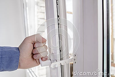 The hand holds the handle of window with restrictor Stock Photo