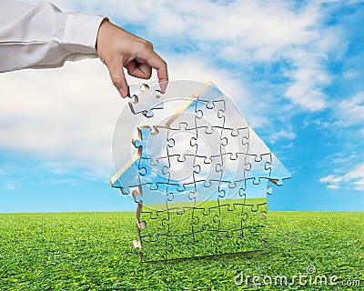 Hand holds the last piece of house puzzle Stock Photo