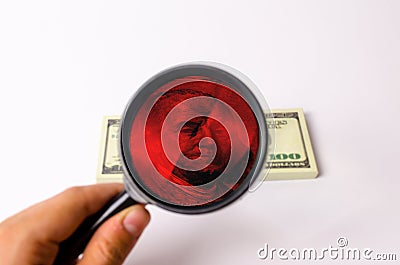 The hand holds a magnifying glass and looks at a dollar Stock Photo