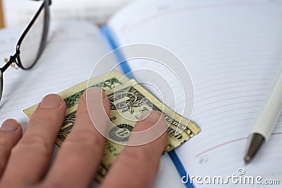 The hand holds the money in the notebook on the desk in the office. A bribe giving. corruption. Dollars for work. work done for mo Stock Photo