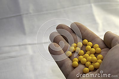 Hand holding a handful of yellow pills Stock Photo