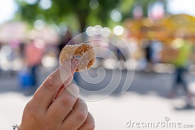 Hand holds up on sugar coated fried mini donut at state fair Stock Photo