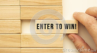 Hand holds a wooden cube with the text ENTER TO WIN Stock Photo