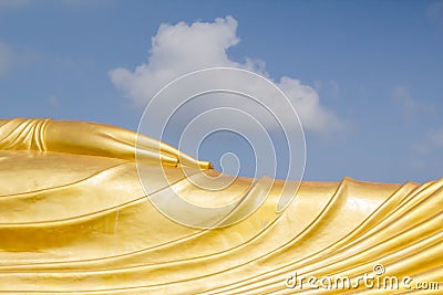 Hand of huge golden sleeping Buddha with blue sky Stock Photo