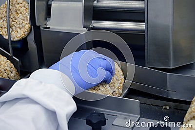 Hand of a human in glove works on conveyor. automatic line for the production of crispy whole grain bread at the factory Stock Photo