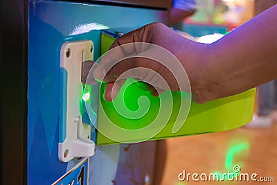 Hand insert a coin to children`s game console In the shoppingmall. Stock Photo