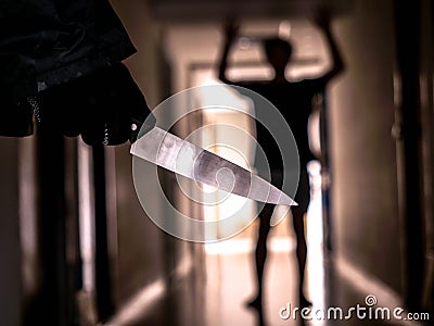 Hand with knife following young terrified in the apartment. man Bandit is holding a knife in hand, Threat Concept, Murder concept Stock Photo