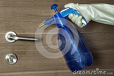 Hand of lady in white gloves that applying alcohol spray to cleaning and disinfection of the door handle. Actions to prevent the Stock Photo