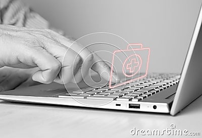 Hand at laptop keyboard and virtual first aid kit. Man searching information about urgent medical care or list of Stock Photo