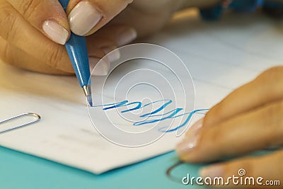 Hand learning lettering in class with blue pen and white paper Stock Photo