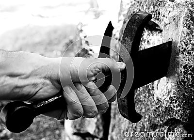 Hand and the legendary Excalibur sword in the stone Stock Photo