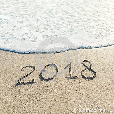 Hand lettering Happy New Year 2018 caption on sand of beach with Stock Photo