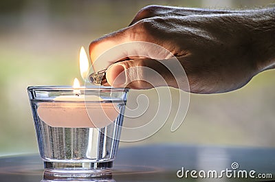 Hand with a lighter lighting a candle Stock Photo