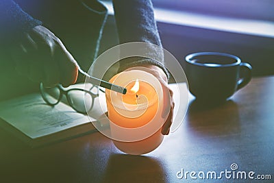 Hand lighting candle before reading book Stock Photo