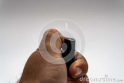 Hand lighting a cigarette lighter on a gray background Stock Photo