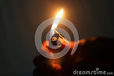 Hand lighting a small fireworks with a match in the night on dark background. Stock Photo