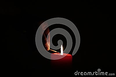 A hand lightning a candle in the dark Stock Photo