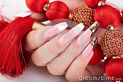 Hand with long artificial white and black french manicured nails and red necklace Stock Photo