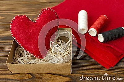 Hand made red felt heart, thread, cloth on wooden background Stock Photo