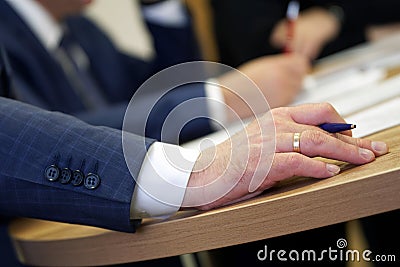 Hand of a male executive holding a fountain pen during a meeting or discussion. Decision making. Filling out documents, Stock Photo