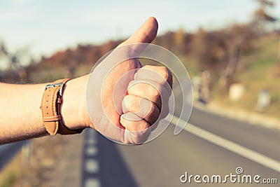 Male hitchhiker holding thumbup on the side of the road Stock Photo