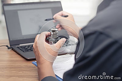 Hand a man hold car thermostat of engine use laptop computer check new part Stock Photo