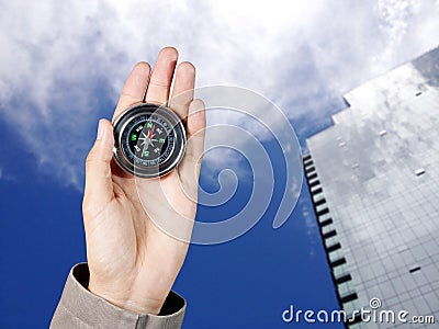 The hand of a man holding a magnetic compass over a city buildings Stock Photo