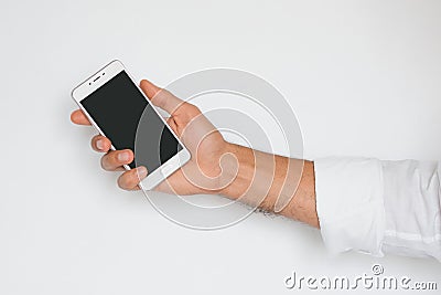 Hand of a man holding mobile smart phone with black display isolated on light gray background. Stock Photo