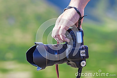 Hand of a man holding professional digital camera on blurred gre Stock Photo