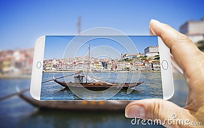 Hand of man holding a smartphone with a picture of a typical portuguese boats used in the past to transport the famous port wine Stock Photo